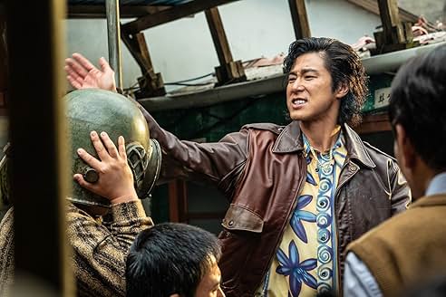 화려한 셔츠와 가죽 재킷을 입은 남성이 군용 헬멧을 쓴 사람을 위협하는 듯 손을 드는 장면