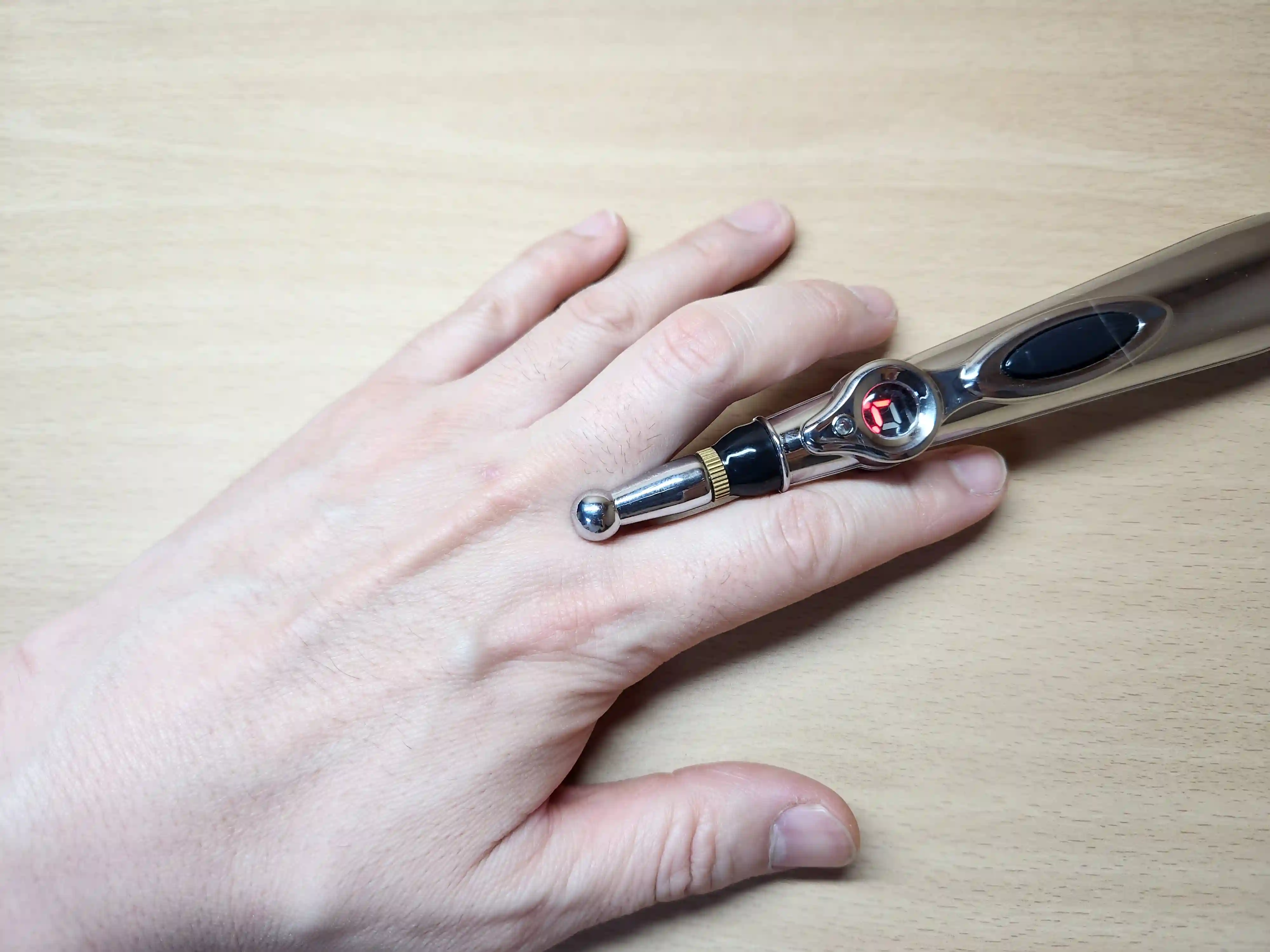 검지와 중지 사이에 EMS 마사지 펜으로 자극하는 이미지