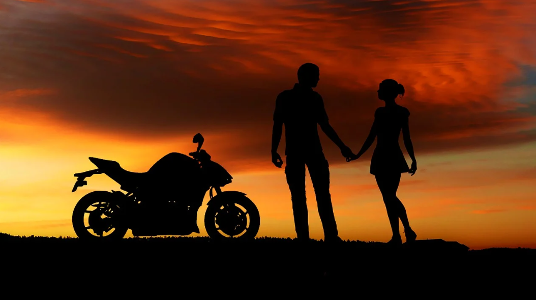 아름다운 석양이 보이고 남녀커플과 오토바이가 있습니다.