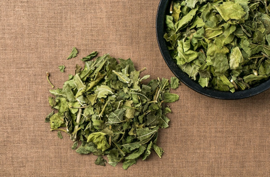 야생에서 채취를 한 뽕나무의 잎인 상엽을 깨끗하게 세척하고 건조시킨 것을 갈색의 바닥 위에 한움큼 놓아두고 그 옆에는 동그란 그릇에 상엽을 가득 담아둔 것을 놓아두고 찍은 사진