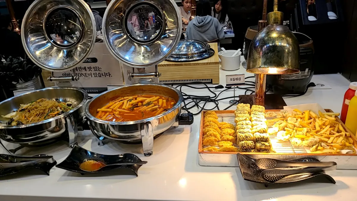 명륜진사갈비-실내-샐러드바에-떡볶이-잡채-튀김류가-세팅되어있다