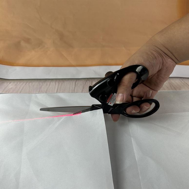 레이저 가위에서 레이저 가이드 빛이 나오고 흰 종이을 자르는 사진