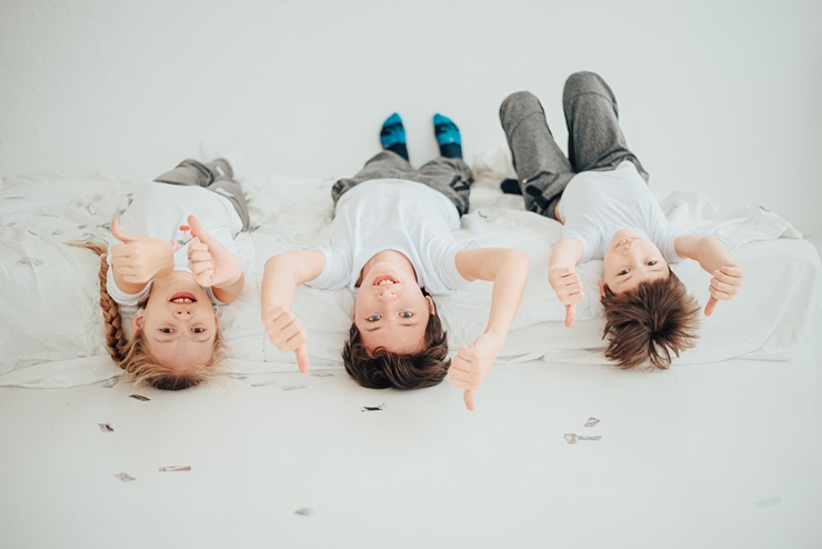 세명의 아이들이 누워서 앞을 바라보며 엄지척 하는 모습