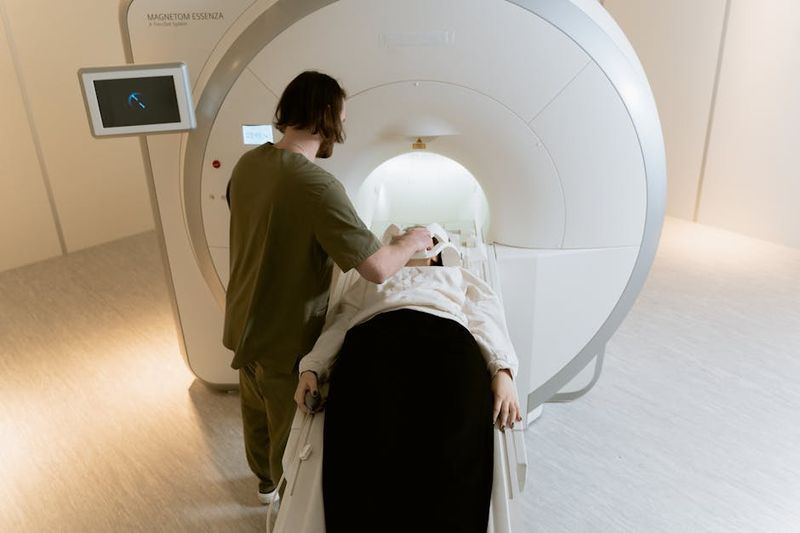 대장암 검진 분변잠혈검사 비용 주기 준비사항 관련 참고 이미지: 의료진이 환자를 MRI 스캔 장비(MAGNETOM ESSENZA)에 준비하고 있는 장면. 환자는 흰색 가운을