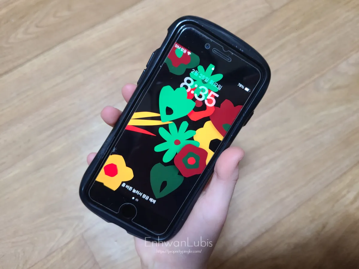 아이손으로-핸드폰-들고있는-알록달록-꽃무니-배경화면의-아이폰-