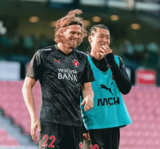 레게머리를 한 조규성 선수가 동료와 함께 경기장에 있는 장면