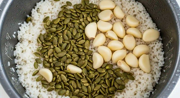 전기밥솥의 잘 익은 밥 위에 호박씨와 마늘이 올려져 있는 모습