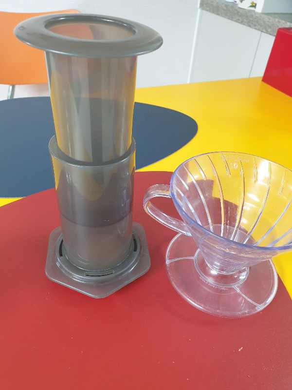 테이블에 에어로프레스(왼쪽)과 하리오 V60 드리퍼가 놓여 있다.