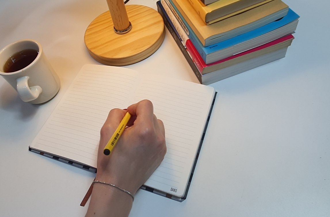 블로그 예약 발행을 상징하는 노트와 펜이 놓인 따뜻한 조명 아래 책상 사진