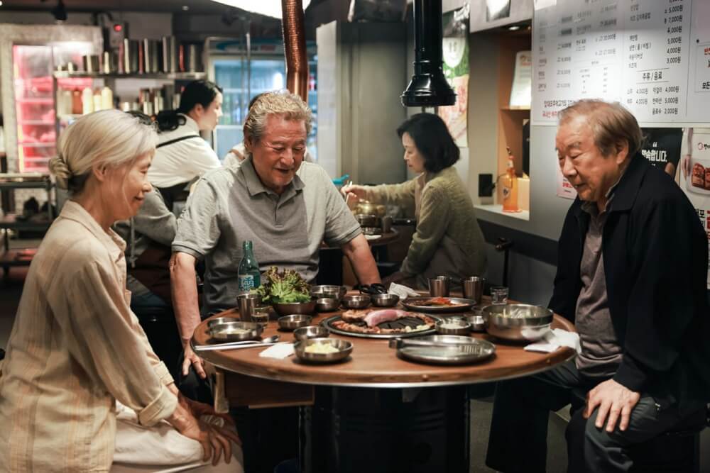 영화 사람과 고기 스틸컷 – 고깃집에서 세 노인이 함께 웃으며 식사하는 따뜻한 장면