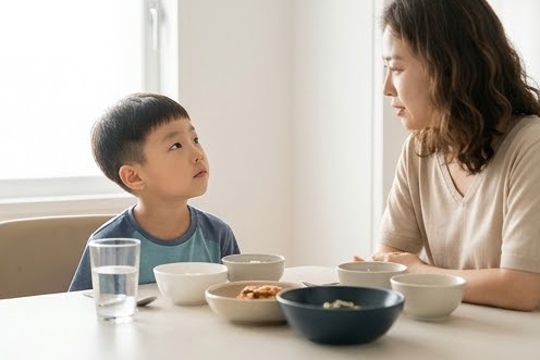 아들이 식탁 너머 엄마를 골똘히 바라보는 장면