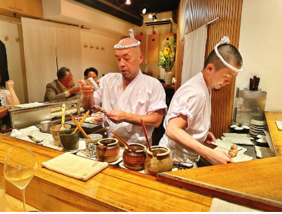 식당에 카운터에 주방장 2명이 흰색옷을 입고 음식을 만들고 있는 모습