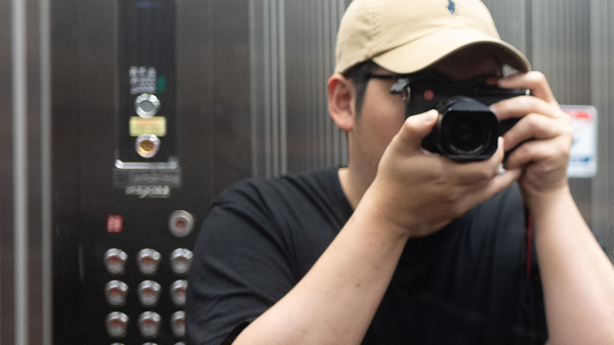 거울에 비친 라이카 Q 카메라와 촬영자의 모습을 담은 셀프 미러 샷. 라이카 Q의 클래식한 디자인과 렌즈 경동의 빨간색 각인이 돋보이는 감성적인 기록.