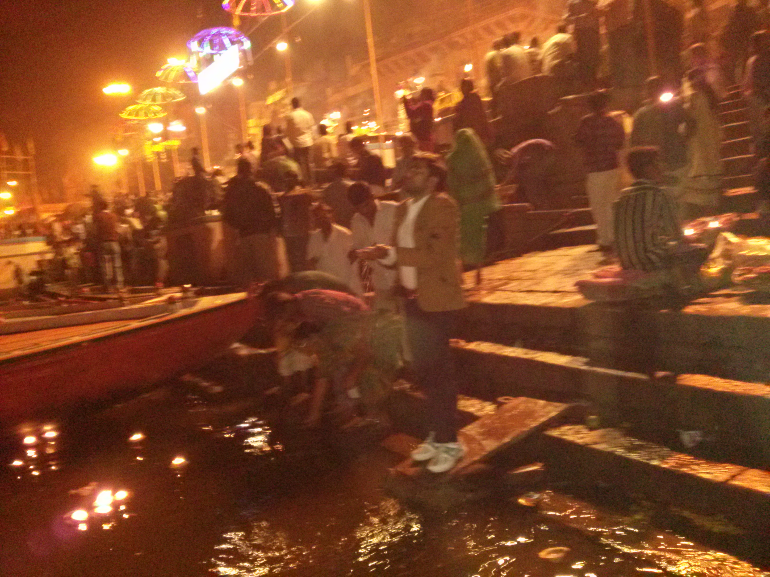 "인도 바라나시 갠지스강 가트에서 밤의 아르띠 뿌자 의식 중 수많은 인파가 모인 가운데 강물을 마시며 신앙심을 표현하는 인도 현지인들의 모습"