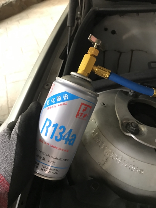 자동차 엔진룸에서 R134a 냉매 캔을 냉매 충전 도구에 연결한 모습 &ndash; 에어컨 가스 보충을 위한 직접 충전 작업