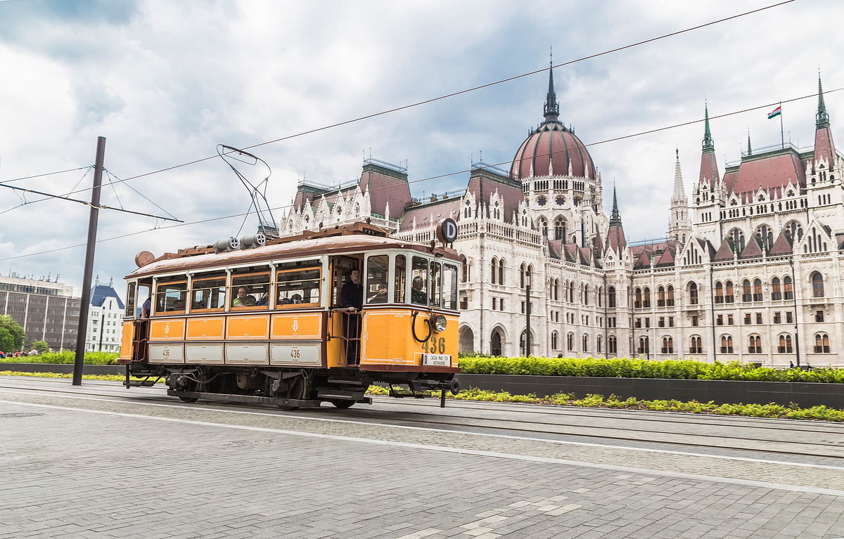 헝가리의 아름다운 건물 앞으로 노란색 트램이 지나가는 사진