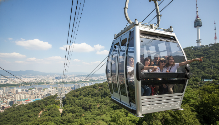 남산서울타워로 향하는 케이블카 안에서 서울의 풍경을 감상하며 즐거워하는 외국인 관광객들의 모습.