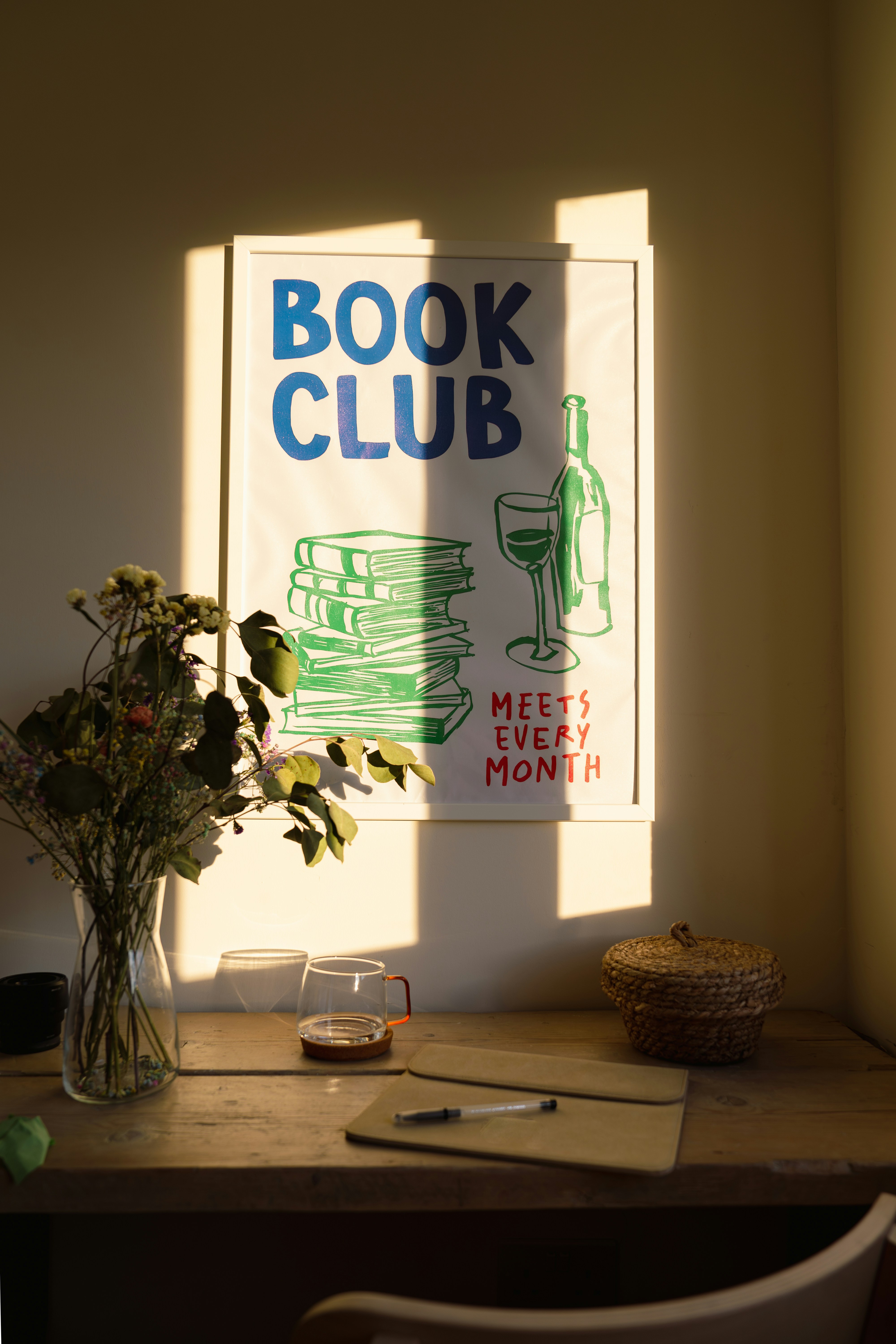 따뜻한 햇살이 비치는 책상 위, 'BOOK CLUB' 포스터와 책 더미, 모임을 상징하는 감성적인 장면