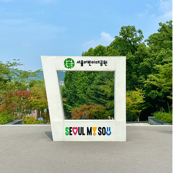 우거진 초록색 나무와 서울 어린이 대공원 안내판