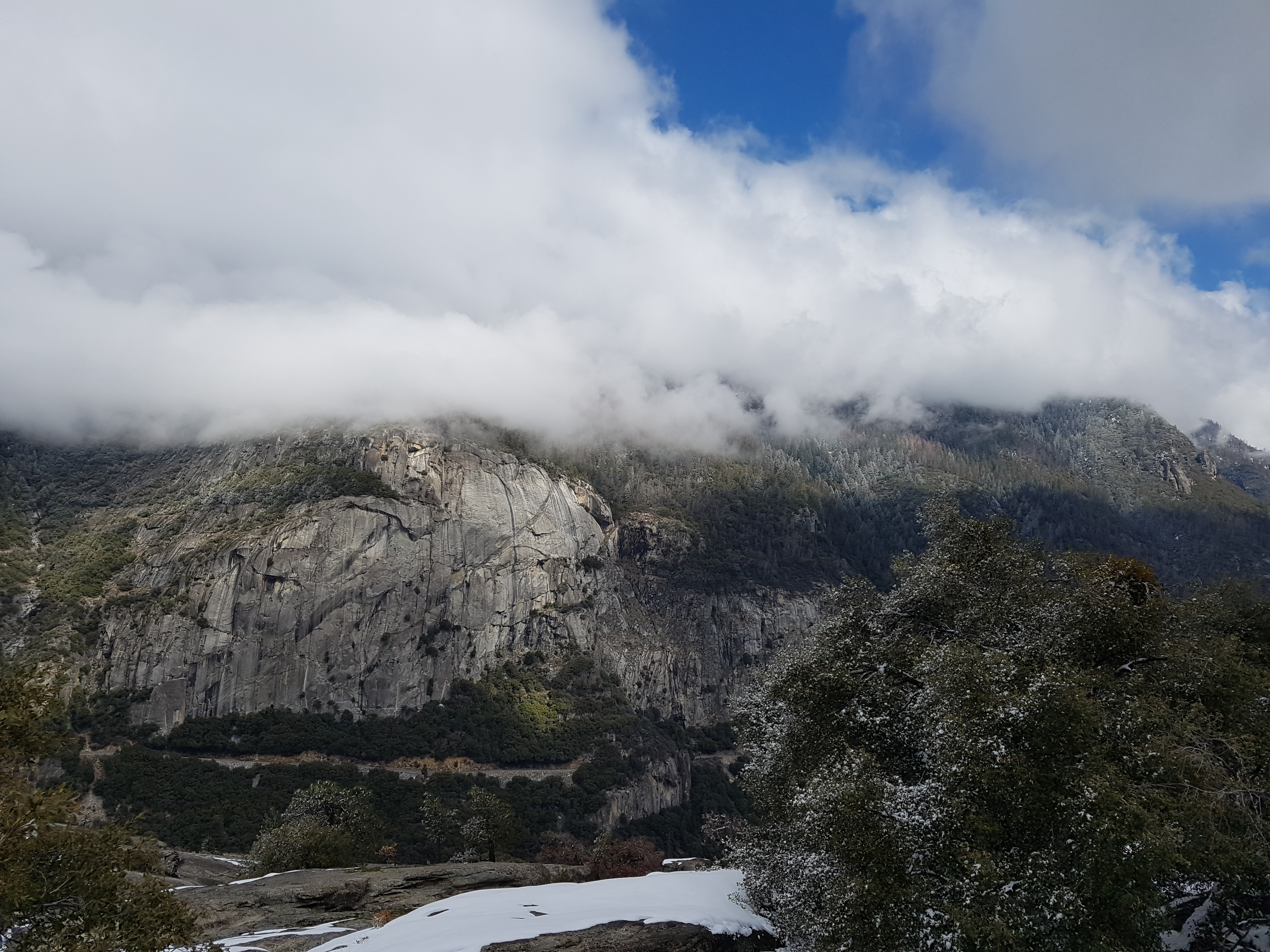 구름이 내려앉은 웅장한 화강암 절벽과 눈이 살짝 쌓인 전경