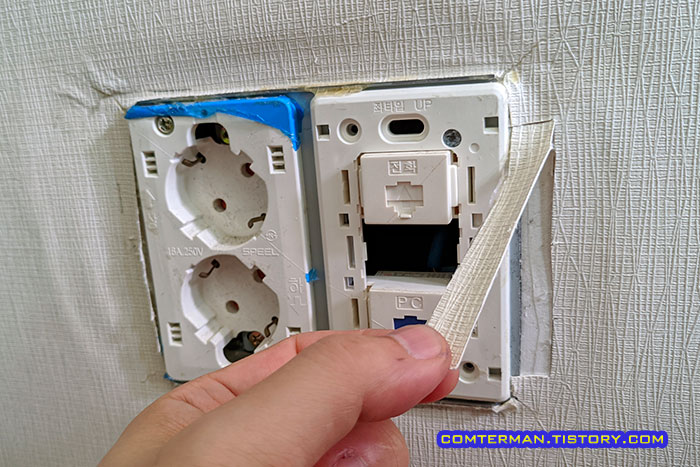 여분의 벽지 조각 콘센트 덮개 아래