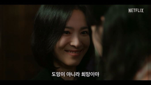 한 여성이 다른 한 여성을 소름끼치는 미소를 띄며 바라보고있다.