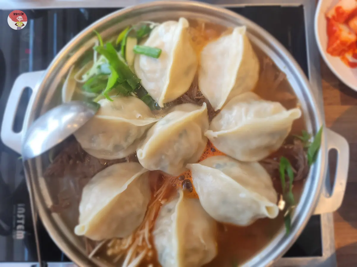 묘향만두 만두전골 만두 8개 밑으로 팽이버섯 등 야채와 우둔살이 깔려있음