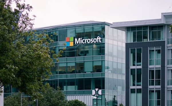 To the left of the glass-walled Microsoft office building are green trees.