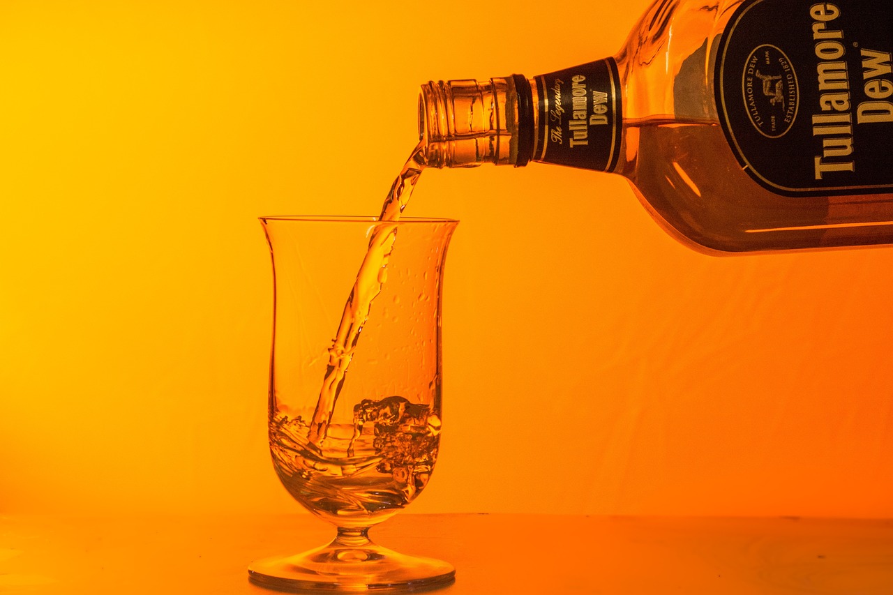 위스키 병에 있는 위스키를 투명한 유리잔에 쏟아내고 있는 것을 확대하여 찍은 사진