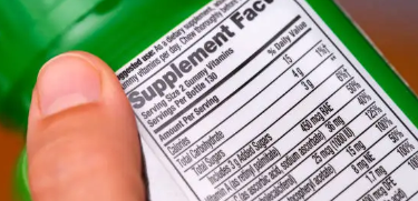 영양제 뒷면의 영양성분표(Supplement Facts)를 꼼꼼히 읽어보는 모습