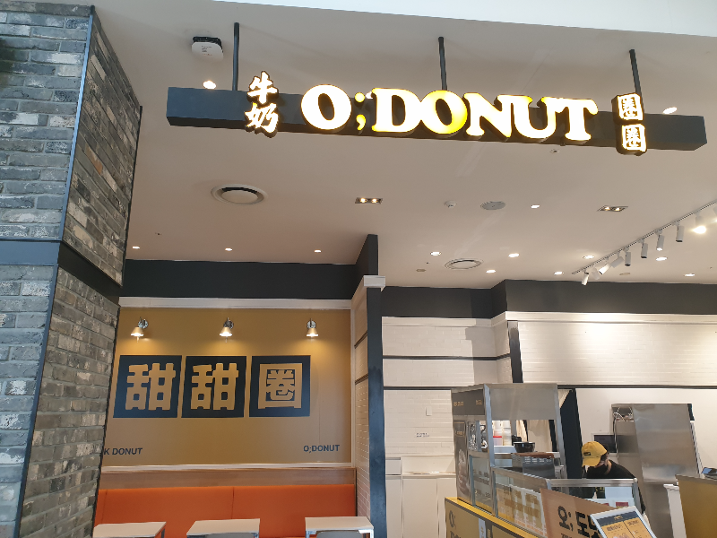 앞에는 한자와 영어로 된 간판. 좌측 안쪽에 노란 벽면과 테이블이 보인다.