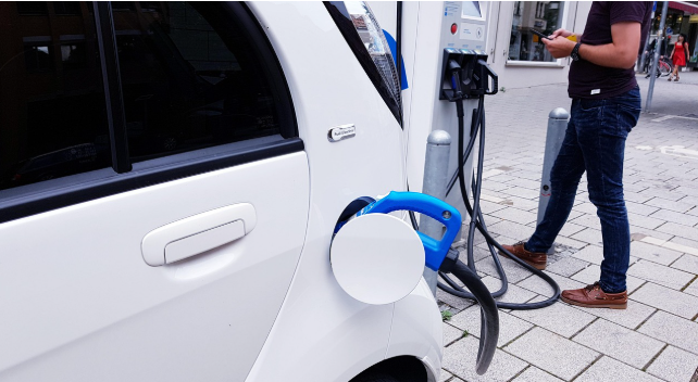 전기차를 충전하면서 스마트폰으로 탄소중립포인트를 확인 중인 남성