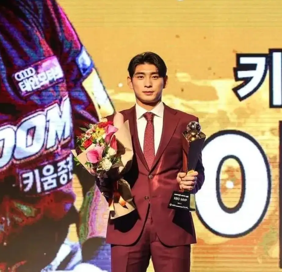 이정후-붉은 정장을 입고 왼손에 꽃다발을 들고 오른손에 트로피를 들고 있는 이정후