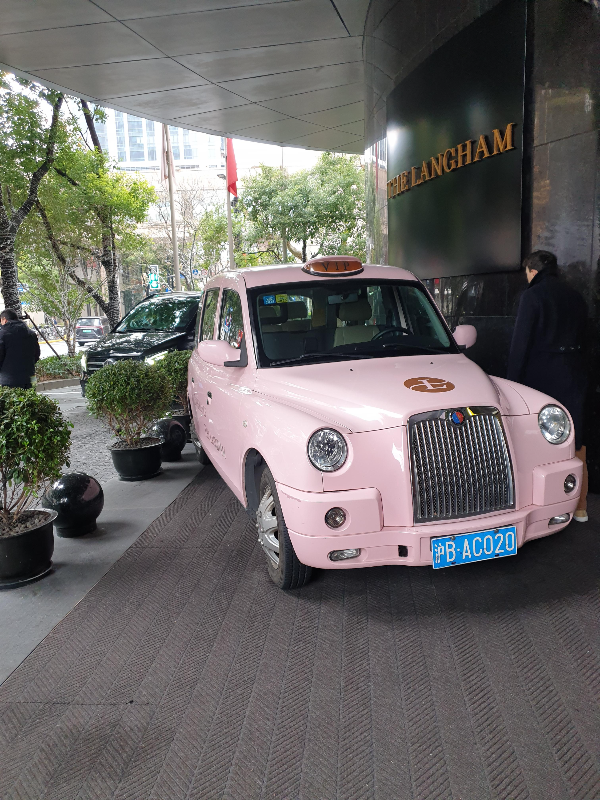 호텔 앞에 분홍색 올드카가 서있다.