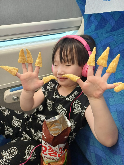 기차에서 유아용 헤드셋을 쓰고 영상을 보는 아이