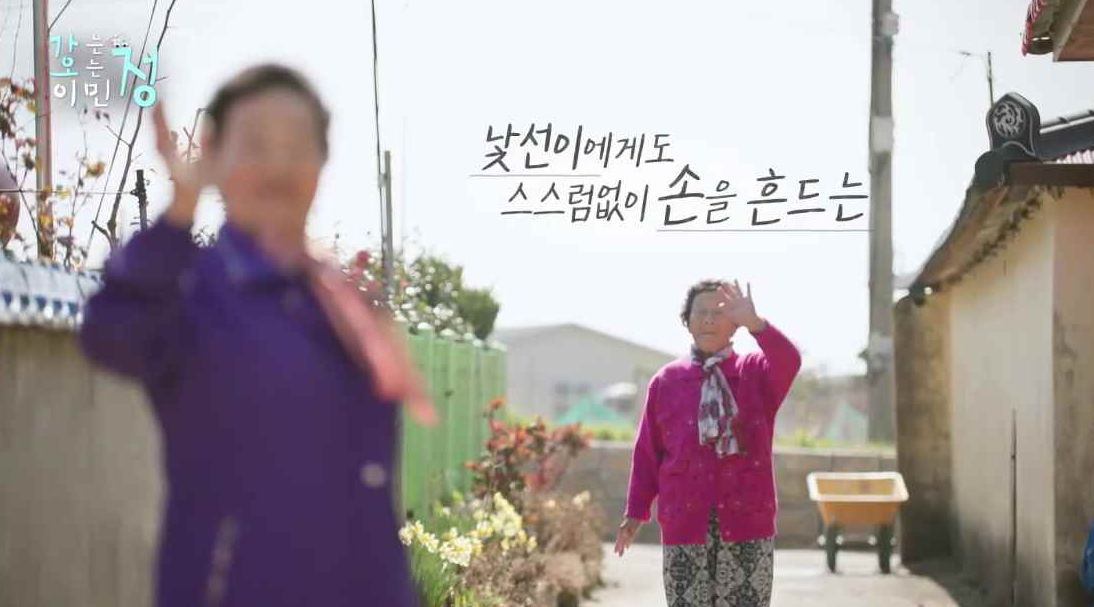 마을 골목에 할머니 두분이 손을 흔드는 장면에 낯선이에게도 스스럼없이 손을 흔드는 자막이 있는 스틸컷