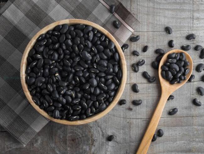 검은콩이 숟가락과 밥공기에 들어있고 바닥에 몇개 흩뿌려져 있다