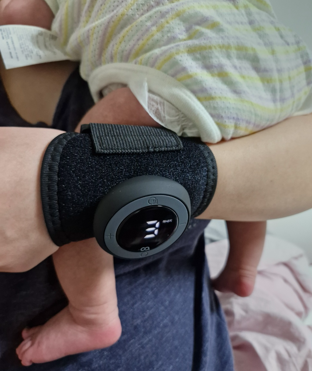 손목에 착용한 히트스팟W 마사지기, 아기와 실제 착용