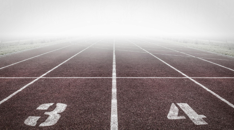 안개 속으로 이어지는 육상 트랙의 출발선, 목표를 향한 시작을 상징하는 이미지