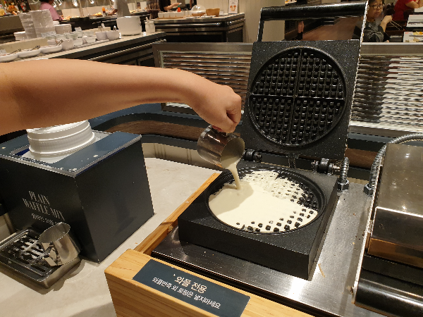 와플 기계에 와플 믹스를 붓고 있는 모습