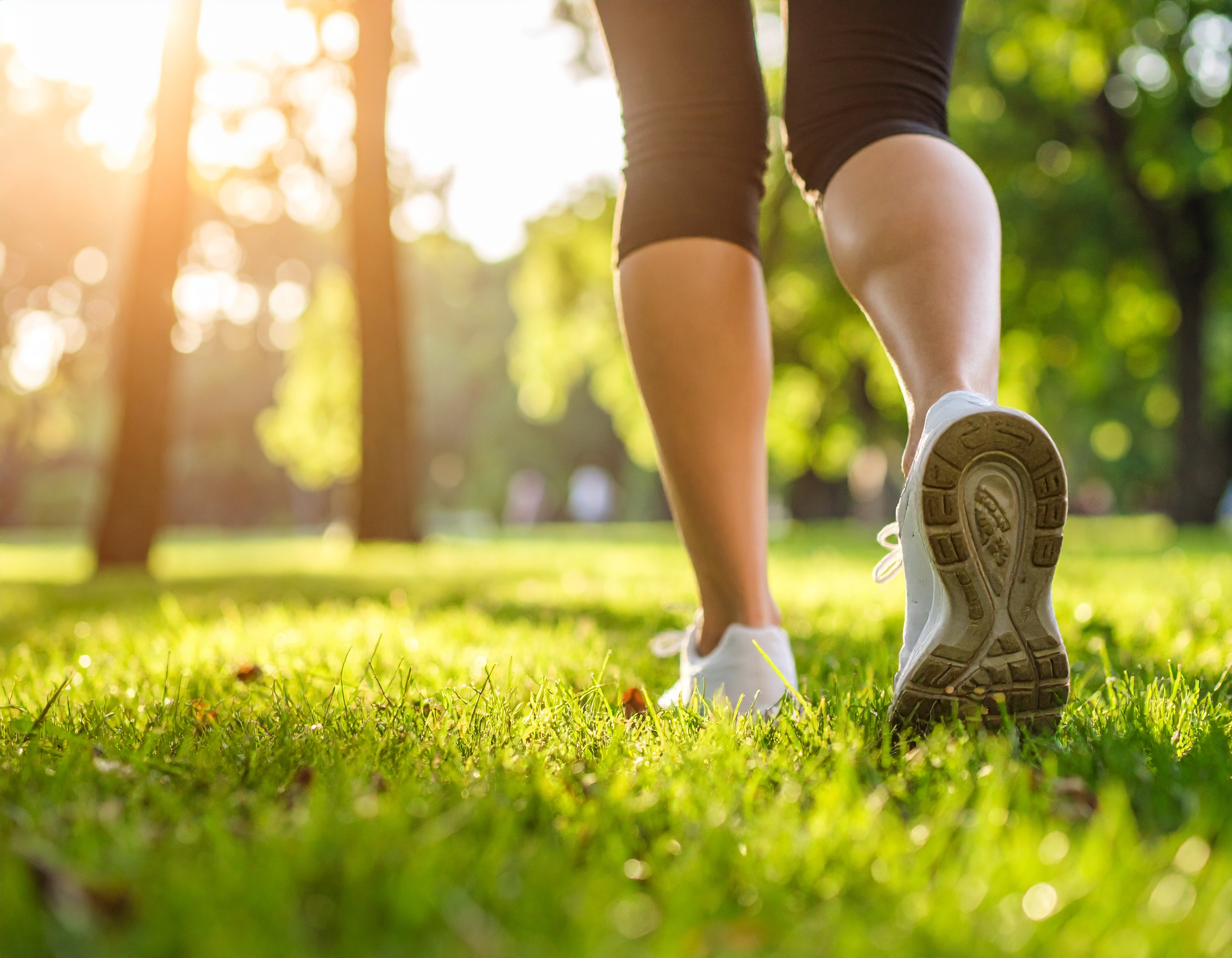 햇살 가득한 공원에서 운동화를 신고 잔디 위를 걷는 모습