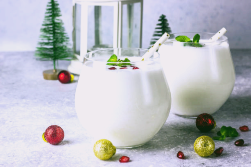 하얀 코코넛 플레이크가 장식된 잔에 담긴 우유처럼 뽀얀 칵테일. 잔 위에 작은 은색 장식이나 식용 진주 알갱이가 놓여 있어 더욱 고급스러운 느낌을 줍니다.