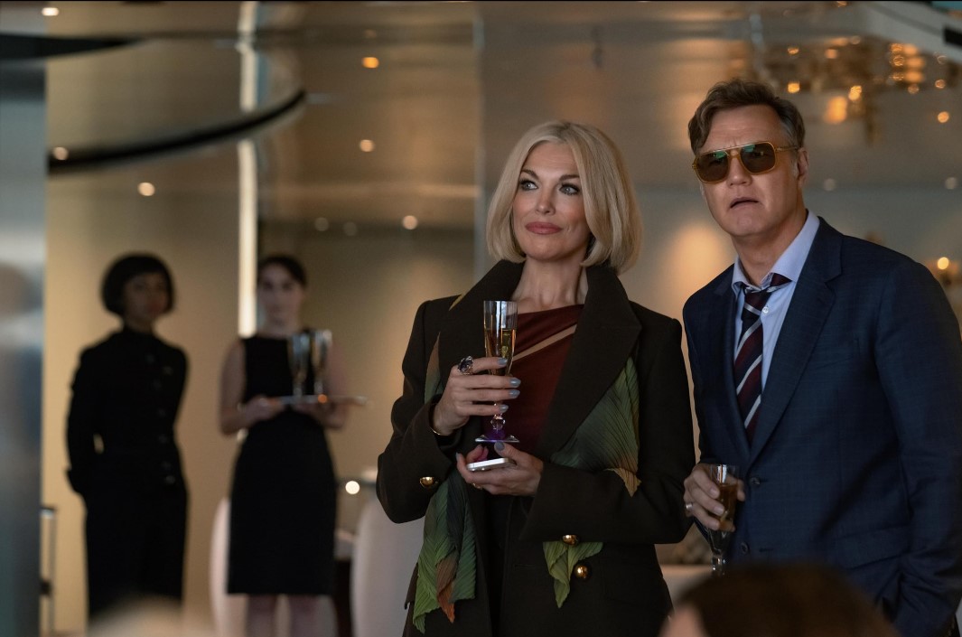 우먼 인 캐빈 10에서 파티 장면에 등장한 한나 웨딩햄|샴페인 잔을 들고 미소 짓는 모습|넷플릭스 미스터리 스릴러