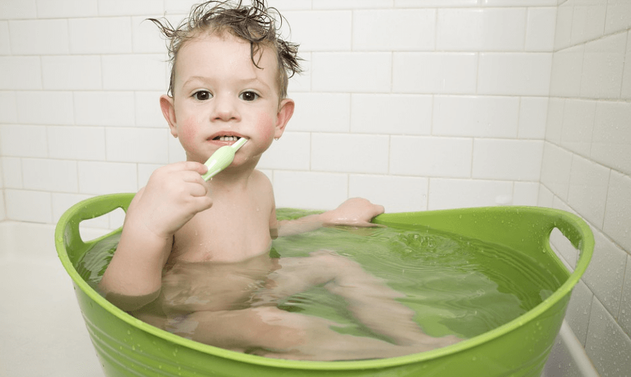 귀여운 아이가 몸을 씻으며 이를 닦고 있다