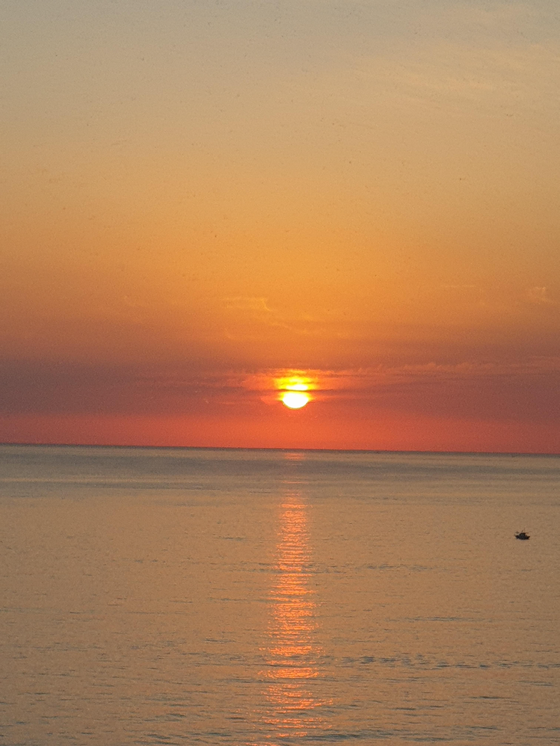 해돋이로 인해 바다가 붉게 물들었다. 해도 하늘도 붉다. 붉은 빛의 길이 바다를 가로질러 창가쪽 나있다.