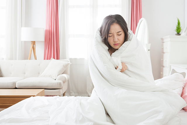 추위에 침대에서 떨고 있는 여성