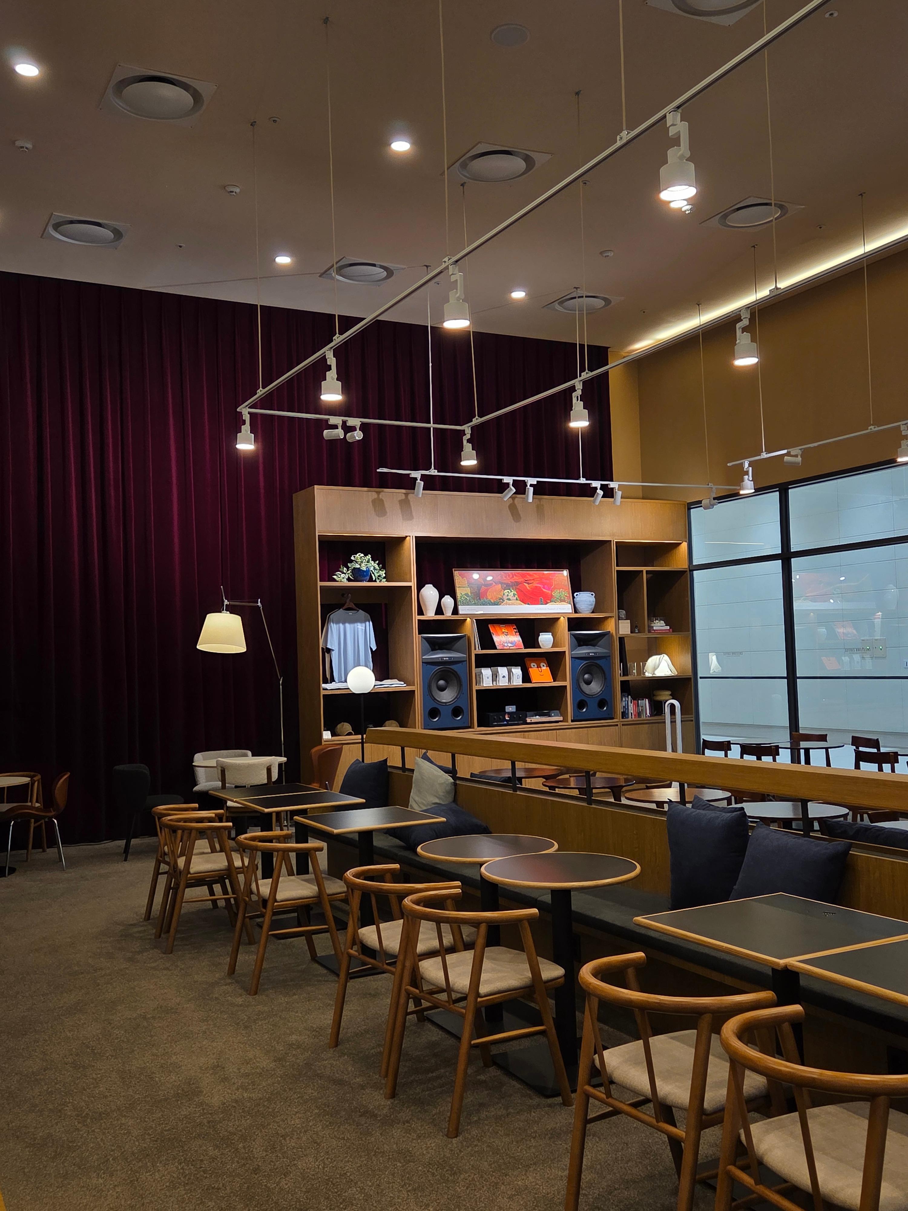 높은 층고와 따뜻한 조명, 우드톤 인테리어가 돋보이는 마곡 크레스타운 커피 매장 전경