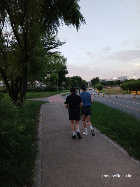 저녁 무렵 산책로에서 두 사람이 나란히 조깅하는 장면