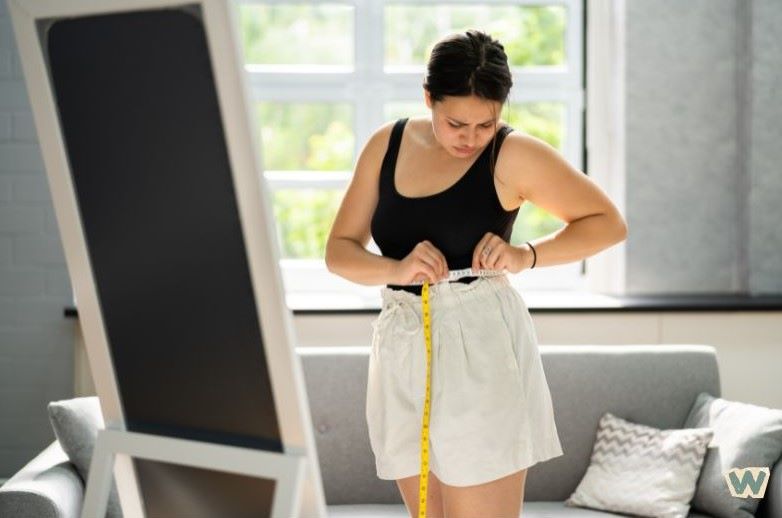 40대 여성이 집에서 허리둘레를 측정하며 중년 다이어트 진행상황을 확인하는 모습 via canva