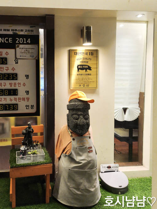 제주덕구 입구 돌하르방 – 앞치마와 모자를 착용한 귀여운 제주 상징